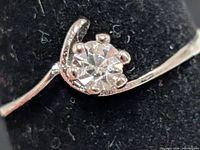 Close-up of silver-tone solitaire ring showing clear stone and band detail