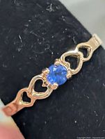 Front view of ring showing blue stone and heart motif band