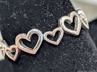 Close-up of silver ring showing open heart design linked around band