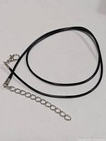 Black cord necklace with lobster clasp and extender chain displayed coiled