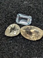 three loose gemstones on black background