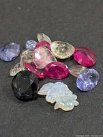 Group of assorted faceted gemstones and carved opal leaf