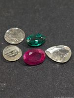 Five assorted faceted gemstones on dark background