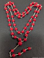 Full view of red coral beaded silver rosary laid in heart shape