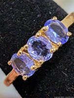 Angled view of ring on display showing three tanzanite stones and prongs