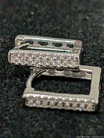 pair of square silver earrings with CZ on black background