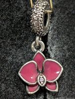 Front view of silver pendant showing pavé stone bail and pink enamel flower
