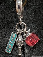 Front view of silver pendant showing bail and three charms
