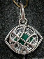 Front view of silver pendant showing geometric openwork and green cabochon