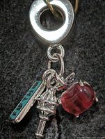 Front view of pendant showing red apple, torch, and FIFTH tag