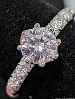 Front view of silver ring displaying round CZ center stone and accented band