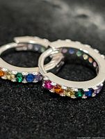 Close-up of both hoops showing multicolor stones and silver finish