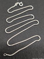 Full view of silver box-link chain laid out straight showing clasp and links