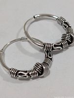 Front view of both silver hoop earrings showing wire-wrap and knotted design