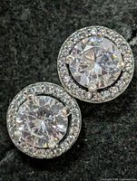 Front view of both earrings showing center CZ stones and halo