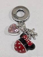 Front view of silver charm pendant showing pink CZ heart, red/black enamel ladybug, silver glove dangle, S925 bail