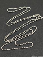 Full view of silver ball chain laid out showing bead style and clasp