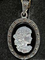 Front view of oval silver pendant with mother-of-pearl cameo and marcasite border