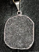 Front view of silver edged dark grey druzy agate pendant showing texture and bail