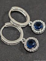 pair of silver hoop earrings with blue CZ halo drops