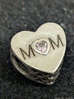 Front view of heart charm showing “MOM” engraving and pink stone