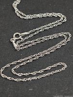 Full view of twisted silver rope chain laid out to show overall length and link style