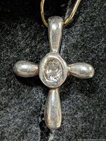 Front view of silver cross pendant showing cubic zirconia stone and overall shape