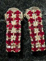 Close-up of both earrings showing red stone clusters and silver prongs