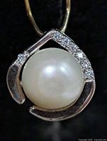 front view of pendant showing pearl and stone-accented frame