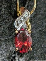 Front view of pendant showing garnet, prongs, swirl with clear stones
