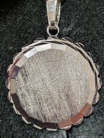 Front view of pendant showing scalloped faceted border and brushed centre