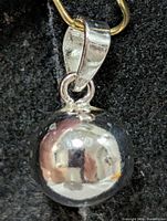 Front view of polished silver sphere pendant showing reflective finish and bail