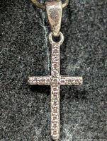 front view of silver cross pendant displaying stones and bail