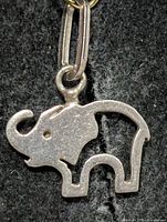 Front view of small silver elephant pendant on dark background