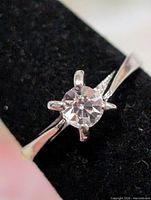 Front view of silver solitaire ring showing round clear stone in four-prong setting
