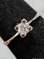 Front view of ring showing clear round stone in four-prong square setting