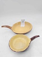 Two matching handled ceramic pans top view showing yellow interiors