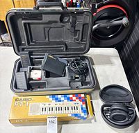 Open hard case showing Canon battery coupler, two battery packs, cables; headphones case on table