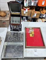 Group shot of wooden jewelry box, metal box open, and glass-top display case