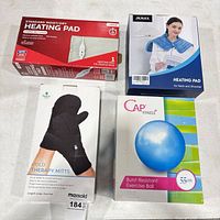 Overview of four boxed items: moist/dry heating pad, JKMAX neck heating pad, NatraCure cold mitts, CAP 55 cm exercise ball
