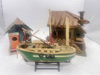 Overall view of the three wooden fishing-themed pieces: model boat, cabin fish shack, bait-shop birdhouse