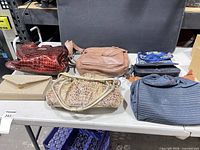 Six handbags and clutches displayed on table