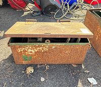 Closed rusty green steel tool box with lid slightly open showing interior