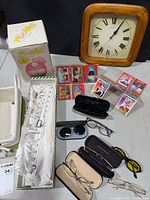 Group shot showing all items: wall clock, Moonies box, skates, eyewear, trading cards, wicker tray