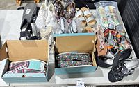 Overview of all footwear on table including TOMS boxes and various sandals and sneakers
