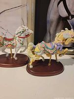 Two Lenox carousel horse figurines showing colors, poles and bases
