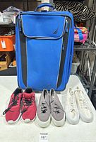 Front view of blue Nautica suitcase with three sneaker pairs lined up