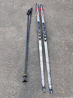 Full view of skis and poles laid on pavement