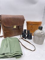 Group view of leather satchel, binoculars, leather case, canteen, folded tarp