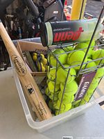 Overall lot showing bat, tennis ball hopper, sealed can, and box with practice balls